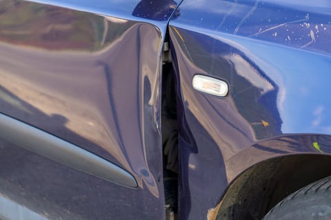 Dented car door before repair