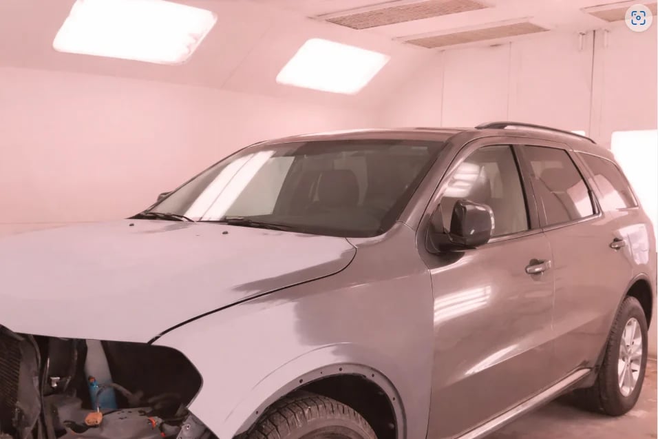 Silver SUV parked in a pink-painted auto service garage with fluorescent ceiling lights